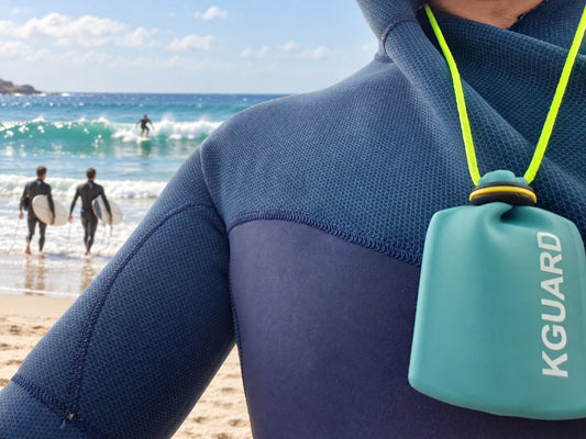 KGUARD Key Pouch compacto sujeto al neopreno de un surfista.